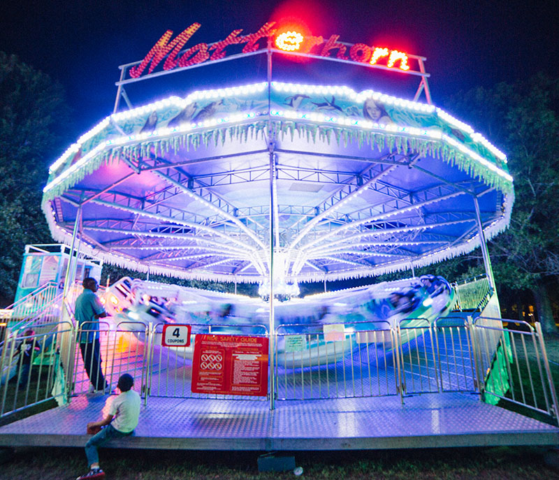 Brightly lit carnival ride in motion at night.